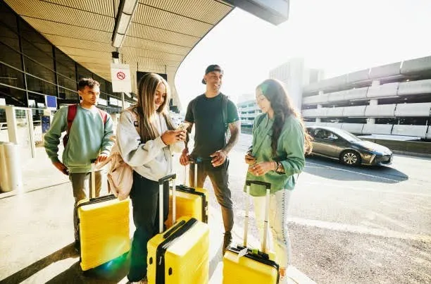 Camp leader helping teenagers with luggage during airport transfer for summer camp